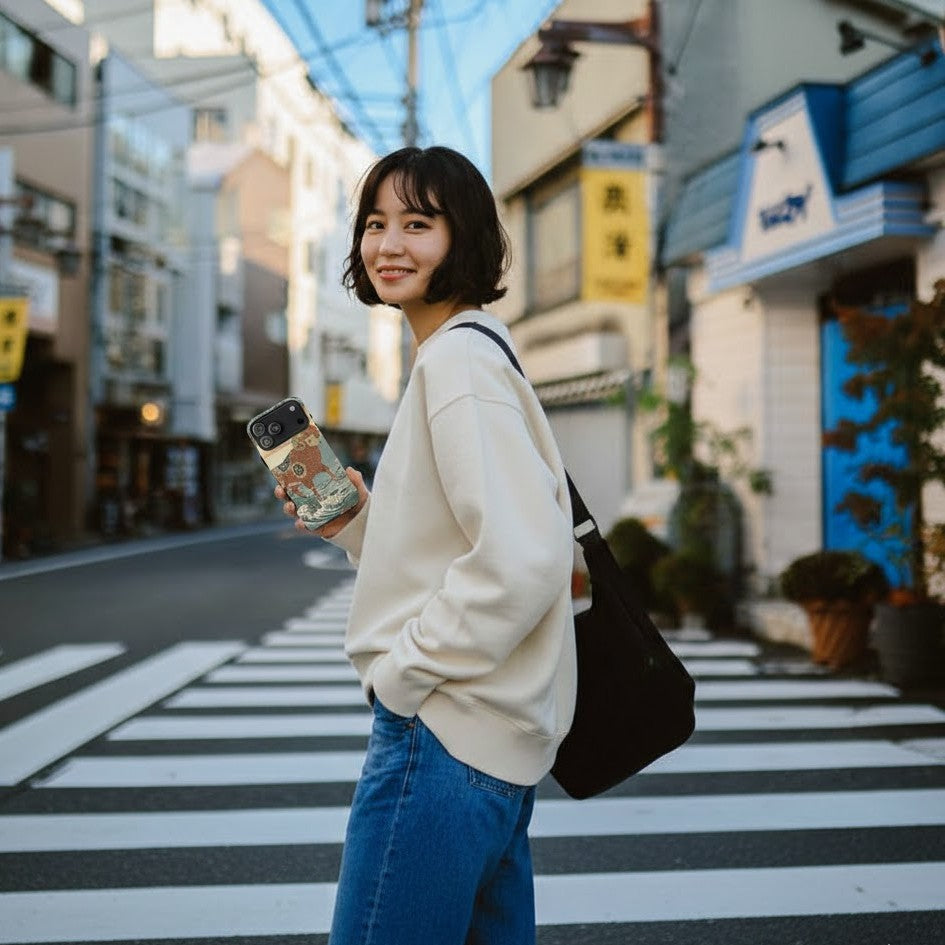 Woman holding a Benirre iPhone 17 Pro Max Phone case with an Aries sheep design in Japanese art style on a street.